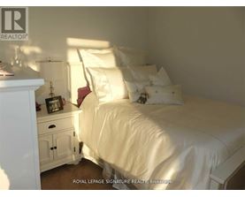 A white bedroom with a bed, nightstand, and lamp.