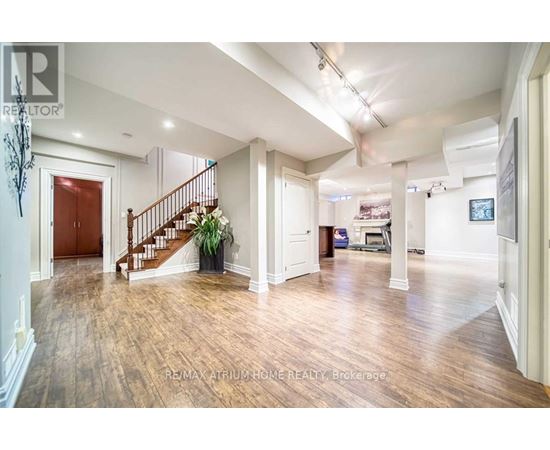 A spacious room with wooden floors and a staircase leading to the upper level.