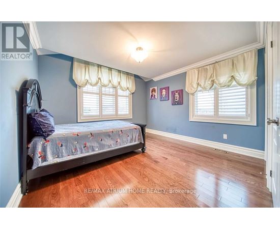 A bedroom with a bed, a window with curtains, and pictures on the wall.