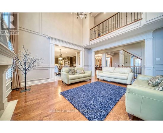 A large open living room with white furniture and a blue rug.