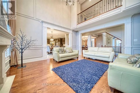 A large open living room with white furniture and a blue rug.