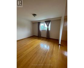 A room with wooden flooring and a window with curtains.