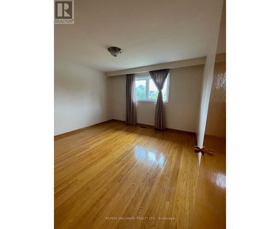 A room with wooden flooring and a window with curtains.
