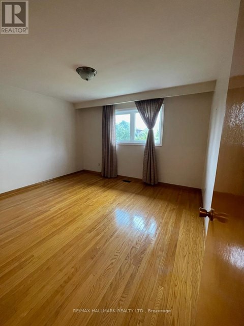 A room with wooden flooring and a window with curtains.