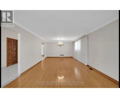 A spacious room with wooden floors and a chandelier.