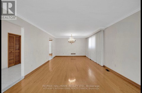 A spacious room with wooden floors and a chandelier.