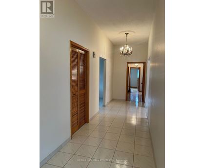 A hallway with a chandelier and a door on the right.