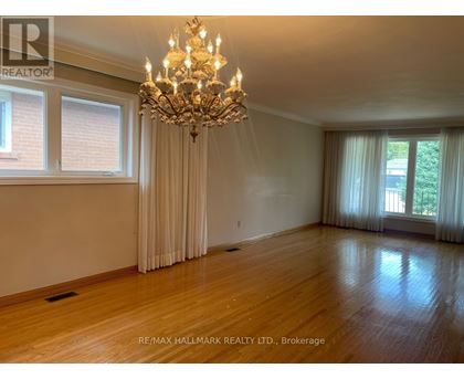 A large, well-lit room with a chandelier and hardwood floors.