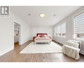 A bedroom with a red bed and a white rug.