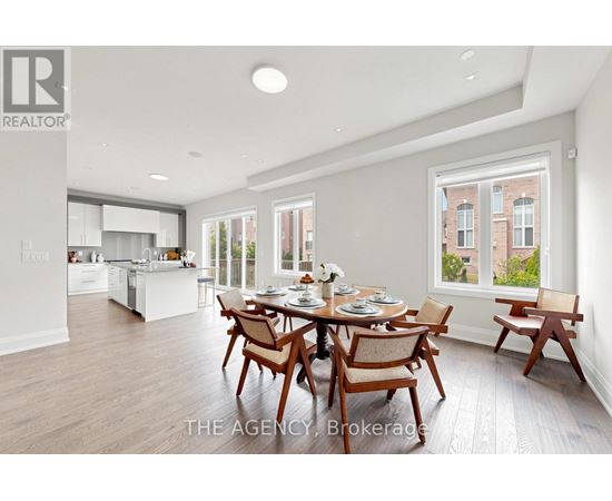 A dining room with a table set for six with a view of a brick building outside the window.