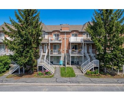 A large apartment complex with multiple balconies and trees in front.