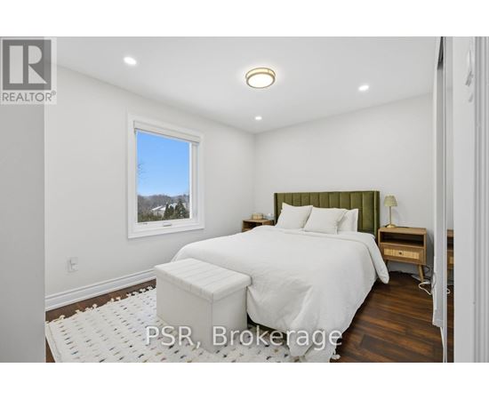 A bedroom with a large bed and a window overlooking the trees.