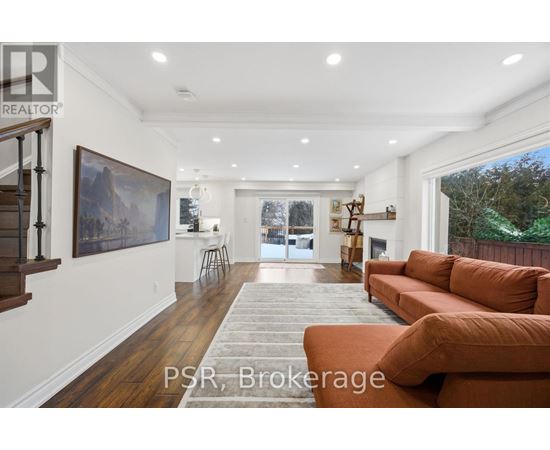 A living room with a brown couch and a painting on the wall.