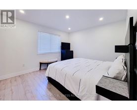 A bedroom with a large bed and a bench under a window.