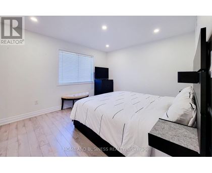 A bedroom with a large bed and a bench under a window.