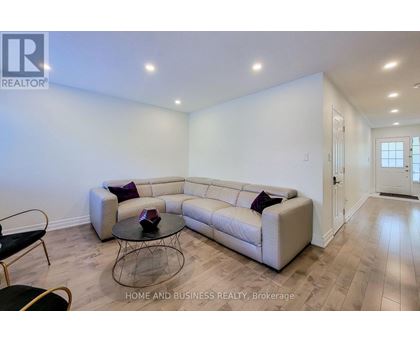 A living room with a white couch and a glass coffee table.