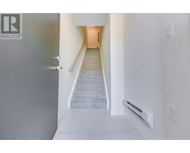 A hallway with a staircase leading to a door.