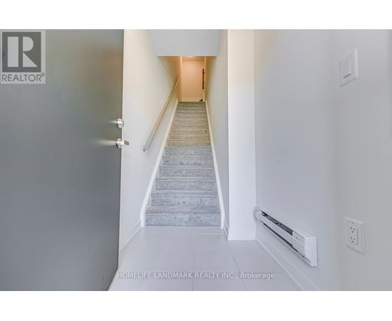 A hallway with a staircase leading to a door.