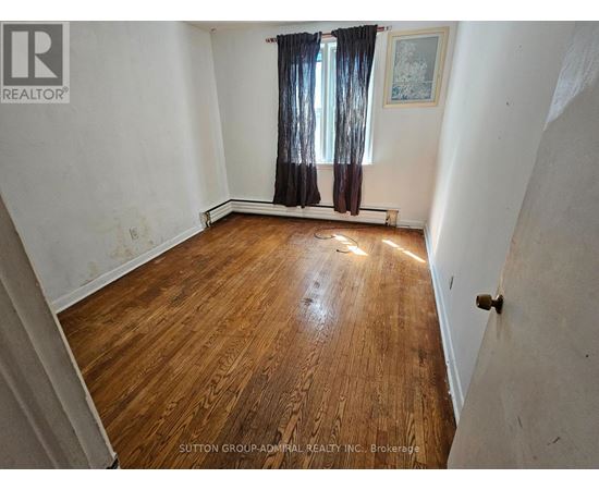 A room with wooden flooring and a window with curtains.
