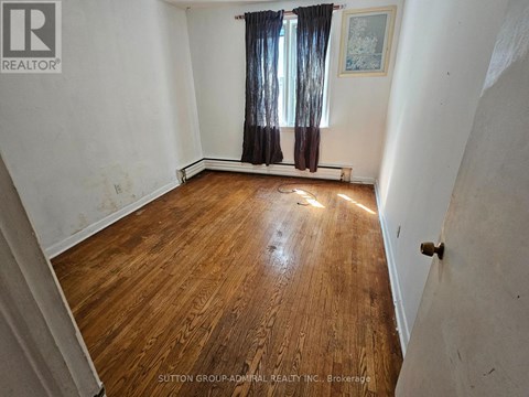 A room with wooden flooring and a window with curtains.
