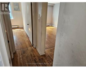 A hallway with wood flooring and white walls.