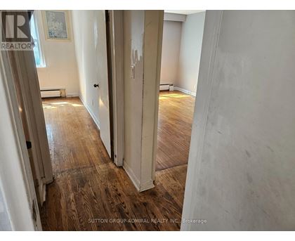 A hallway with wood flooring and white walls.