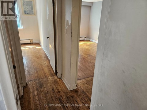 A hallway with wood flooring and white walls.