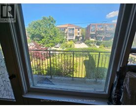 A view from a window looking out at a green lawn and buildings.