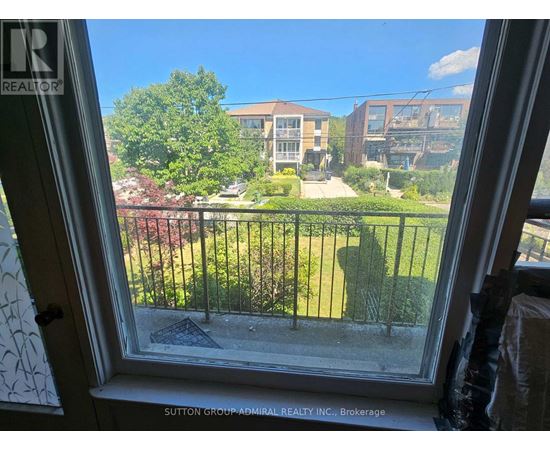 A view from a window looking out at a green lawn and buildings.