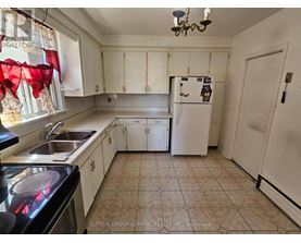A kitchen with a refrigerator, sink, and cabinets.