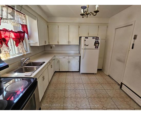 A kitchen with a refrigerator, sink, and cabinets.