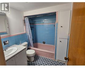 A bathroom with blue tiles and a pink bathtub.
