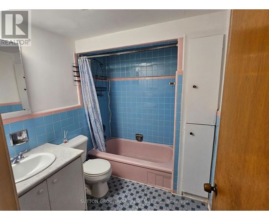 A bathroom with blue tiles and a pink bathtub.