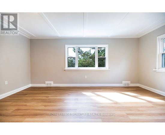 A room with wooden floors and a window showing trees outside.