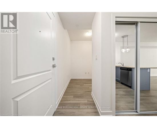 A hallway with a white door and a glass door leading to a kitchen.