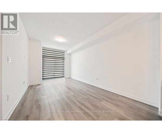 A spacious room with wooden flooring and white walls.