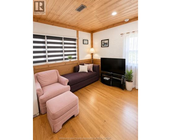 A living room with a purple couch, a pink chair, and a flat screen TV.