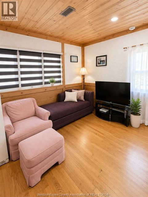A living room with a purple couch, a pink chair, and a flat screen TV.
