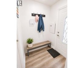A hallway with a bench, coat rack, and a plant.