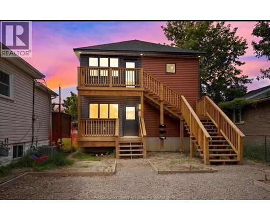 A two-story wooden house with a balcony and stairs leading to the upper level.