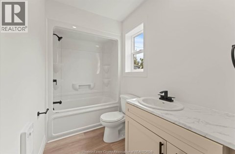 A white bathroom with a toilet, sink, and bathtub.