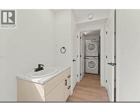 A bathroom with a sink and a washing machine in the background.