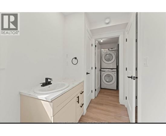 A bathroom with a sink and a washing machine in the background.