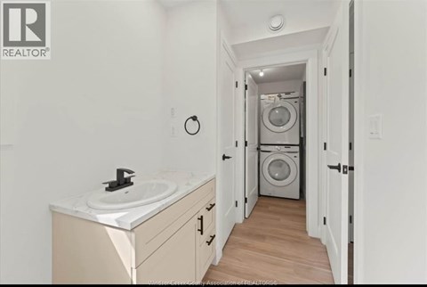 A bathroom with a sink and a washing machine in the background.