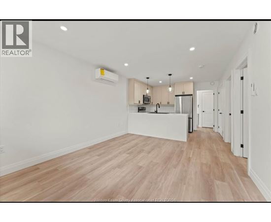 A spacious kitchen with white cabinets and a wooden floor.
