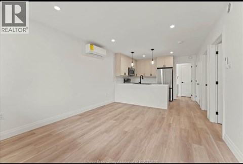 A spacious kitchen with white cabinets and a wooden floor.