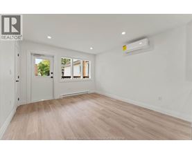 A spacious room with a door, a window, and a wall-mounted air conditioner unit.