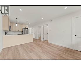 A spacious kitchen with light wood flooring and white walls.