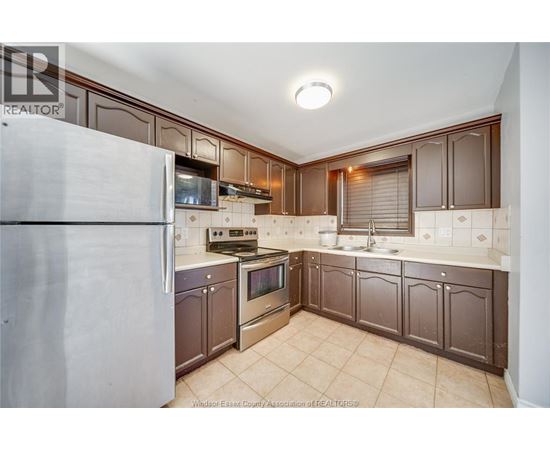 A kitchen with brown cabinets and a white refrigerator.