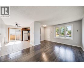 A spacious room with wooden floors and a ceiling fan.